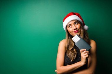 Tatillerin hayalini kuruyorum. Elinde uçak bileti olan ve Noel tatili boyunca seyahat etmeye hazır gülümseyen İspanyol kadın.