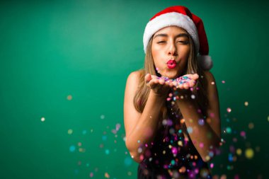 Mutlu Noeller! Neşeli genç kadın konfeti üflüyor ve kutlama yaparken eğleniyor. 