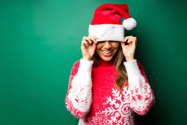 Noel 'de eğleniyoruz. Neşeli genç bir kadın Noel Baba şapkasıyla gözlerini kapatıp gülümsüyor. 