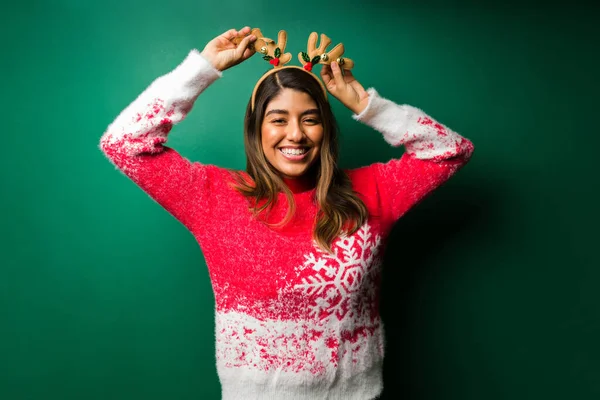 Güzel bir kadın ren geyiği Noel şapkası takıyor ve kutlama yaparken eğleniyor. 