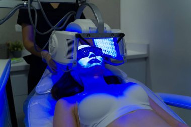 Yaşlanma karşıtı prosedür. 20 'li yaşlarda sağlıklı bir kadın LED maskesiyle kırışıklıkları önlüyor. 