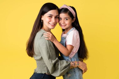 Aile bağı. Neşeli İspanyol anne ve kızının kucaklaşması. Güzel anne ve uzun saçlı küçük kız