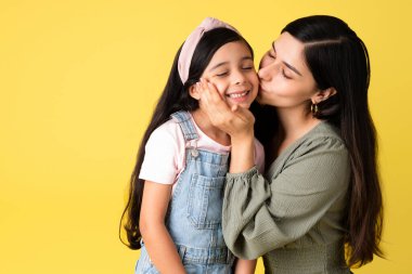 Kendini adamış anne, sevimli küçük kızını öperken aile anlarını paylaşıyor.