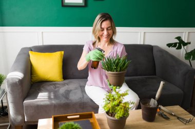 Evde bahçe işleriyle uğraşırken gülümseyen heyecanlı olgun bir kadın. Yaşlı kadın çiçeklerini suluyor.