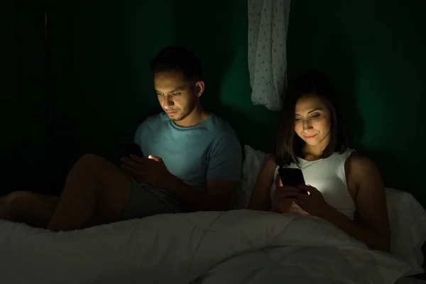 Aantrekkelijk Koppel Dat Nachts Bed Zit Terwijl Hun Smartphones Sms — Stockfoto