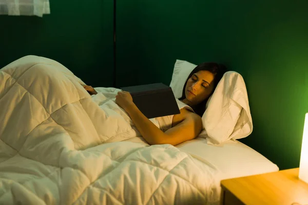 疲惫的年轻女人拿着一本书睡着了 美丽的女人在床上看书后睡着了 — 图库照片