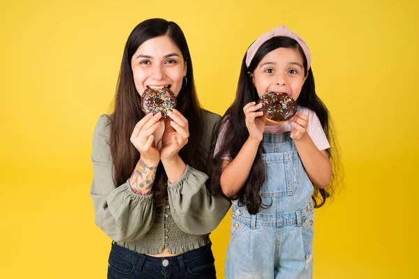 空腹の美しいお母さんと可愛いです女の子食べるチョコレートドーナツ一緒に — ストック写真