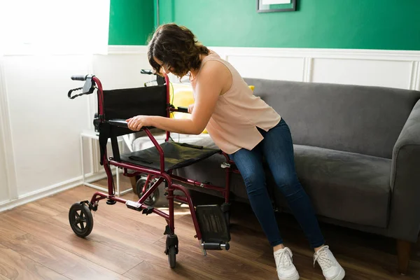 一个残疾年轻人从沙发上走到她的轮椅上 在家的残疾人 — 图库照片