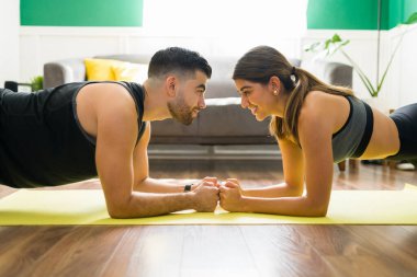 Seninle çalışmayı çok seviyorum. Keyifli genç bir kadın ve erkek spor yapmak için bir kalas yaparken gülümsüyor.