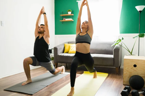 Doing yoga to start the day. Fitness couple in sportswear in a crescent lung pose in the living room
