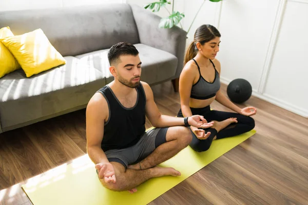 We love yoga. Relaxed young couple in an easy pose practicing breathing exercises and meditating together