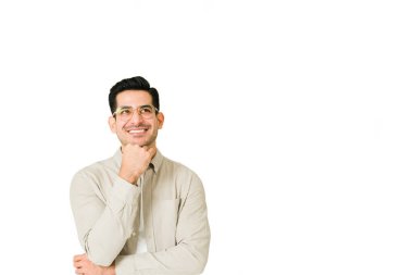 Gülümseyen genç adam, yukarı bakarken ve zekice bir fikir düşünürken hayal kuruyor. 