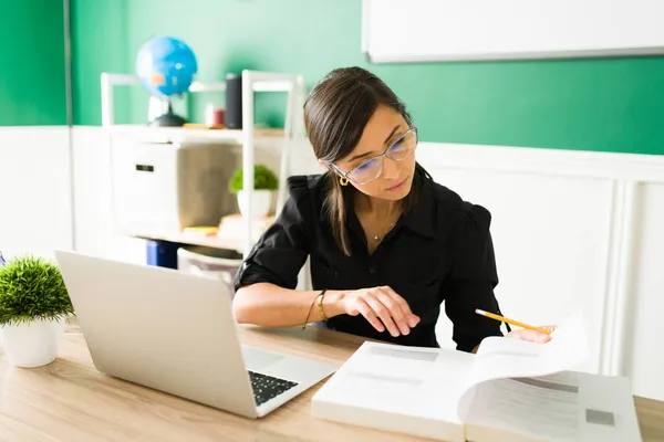 有魅力的年轻女子戴着眼镜学习 同时计划在家里用课本和笔记本电脑上课 — 图库照片