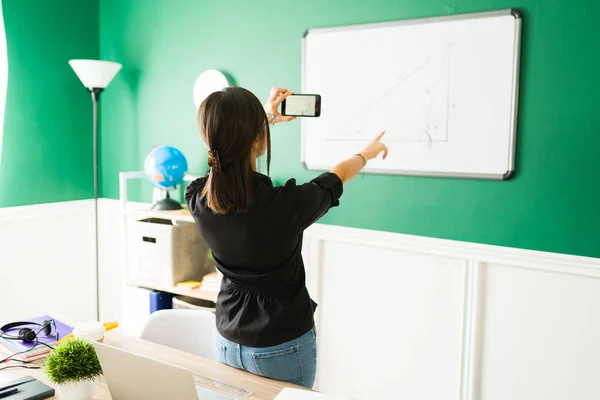 在虚拟课堂上教代数的年轻女人 女教师用她的电话生活流在线课程 — 图库照片