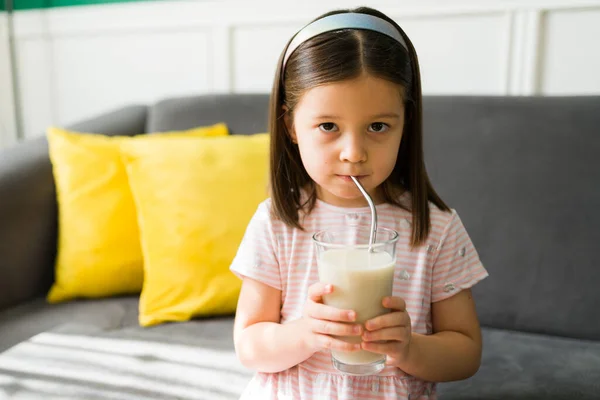 早上在家里吃早饭时 漂亮的小女孩用稻草喝了一杯牛奶 — 图库照片