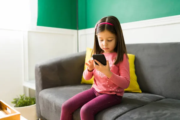 Adorable Elementary Girl Sitting Couch Using Her Parents Smartphone Play — Stock Photo, Image