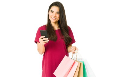 Alışveriş merkezinde alışveriş yaparken telefonuna gülümseyen ve mesaj atan beyaz bir kadının portresi. 