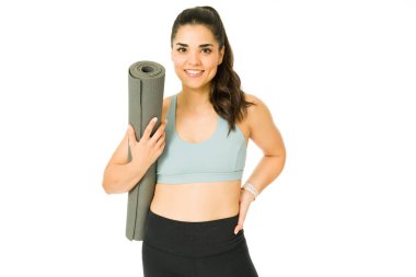 Aktif giyimli muhteşem kadın kardiyo antrenmanına hazır. Egzersiz minderiyle yoga yapacak olan genç bir kadın.