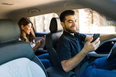 Neşeli sürücü akıllı telefondaki GPS haritasına bakarken bir kadını gideceği yere araç paylaşımı uygulaması kullanarak götürüyor. 