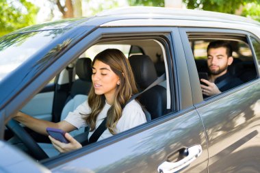 Latin kadın ve kadın sürücü, bir yolcuyu gideceği yere bırakırken akıllı telefonundaki GPS haritasına bakıyor. 