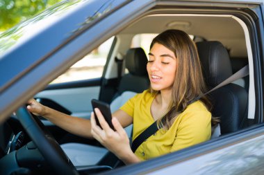 Güzel bir kadın trafikte mahsur kalmışken arabasını sürüyor ve telefonla konuşuyor.