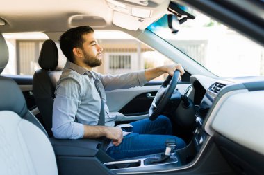 30 'lu yaşlarda çekici bir gencin yeni arabasını sürüşünün keyfini çıkarırken yan görüntüsü.  