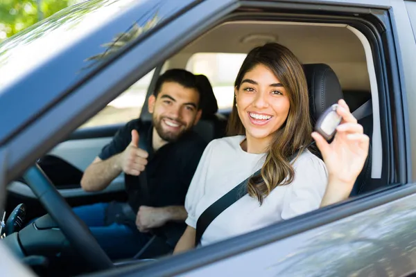 新しい車を購入した後 彼女の鍵を示す豪華な女性 興奮したカップルが親指をあげて彼らのレンタカー — ストック写真