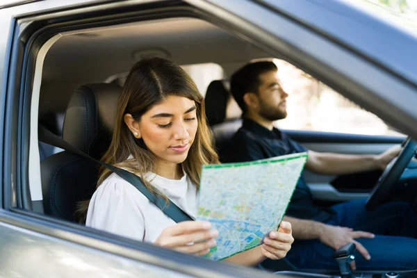 美しいですヒスパニック女性見ながら地図で彼女のボーイフレンドと一緒に車の中でロードトリップ — ストック写真