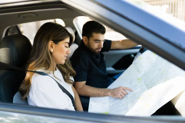 魅力的なカップルは 道路側で停止し 車のロードトリップ中に方向を検索するための地図を見て — ストック写真