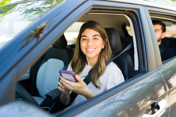 女性ドライバーの笑顔とカープールサービスアプリで乗客の乗車を受け入れながら目の接触を作ります — ストック写真