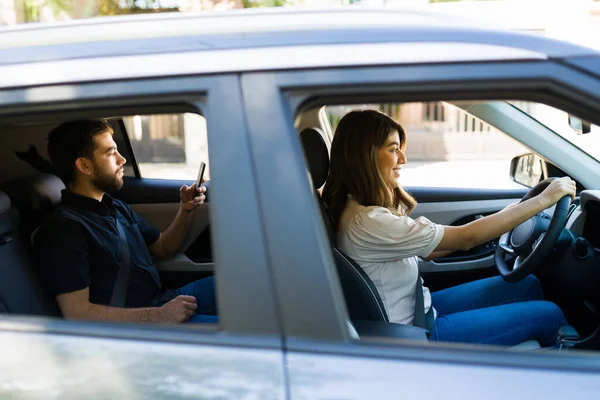 男の乗客を運転しながらアプリ上で新しい乗り心地を受け入れる陽気な若い女性と女性のドライバー — ストック写真