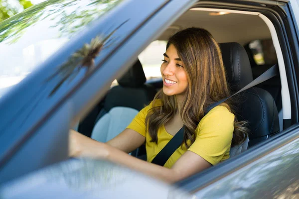 彼女の車を運転しながら幸せな気分でシートベルトを持つラテン女性の側面図 — ストック写真