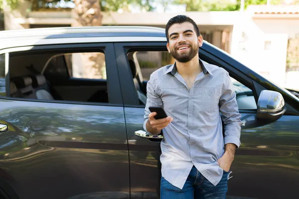 外の黒い車にもたれている間 彼のスマートフォンとテキストメッセージを使用して若い男を笑顔 — ストック写真
