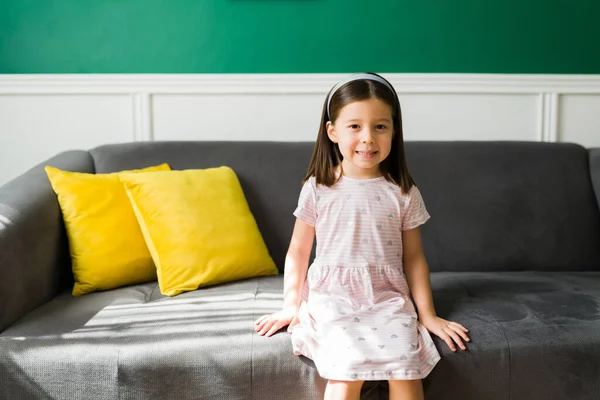 Hermosa Niña Vestido Rosa Sonriendo Sentada Sofá Casa Mientras Espera — Foto de Stock