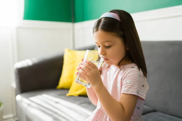 渴可爱的孩子在家里沙发上休息的时候喝了一杯水 白种人小女孩在炎热的一天喝水 — 图库照片