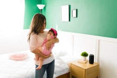 Ebeveynlik kavramı. Yorgun genç bir anne yeni doğmuş bebeğini kucaklarken onu sakinleştirmeye ve uyutmaya çalışıyor.