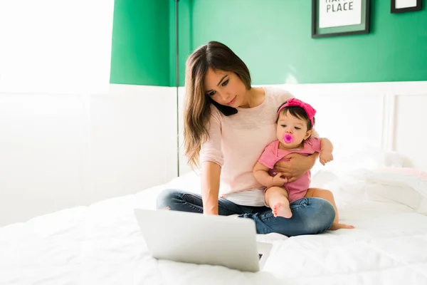 아기를 돌보면서 여자가 일하고 일하는 엄마가 전화를 노트북으로 타자를 — 스톡 사진