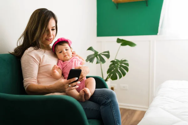아기와 의좋은 아기와 무릎에 미소를 스마트폰으로 문자를 보내는 어머니 — 스톡 사진