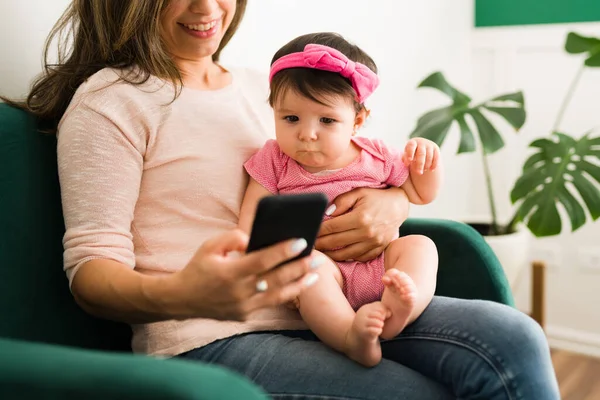 Biała Młoda Mama Pokazuje Wideo Swojej Córeczki Smartfonie Podczas Siedzenia — Zdjęcie stockowe