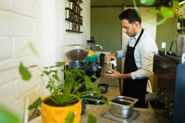 Modern bir hippi kafesinde bir müşteriye kahve yapan Latin asıllı yakışıklı bir barista. 