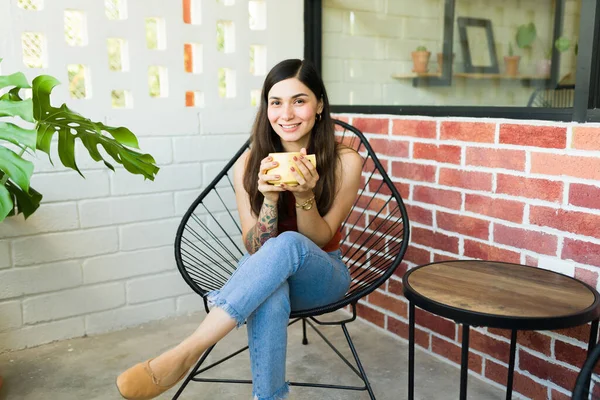 Atrakcyjna Latynoska Uśmiechnięta Nawiązująca Kontakt Wzrokowy Siedząc Przed Hipsterską Kawiarnią — Zdjęcie stockowe