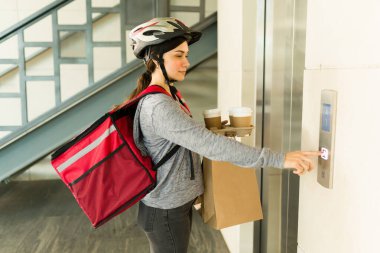Güzel bir teslimatçı kadın apartmana geliyor ve asansörle yemek servisi yapıyor.