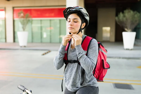 安全ヘルメットをかぶって自転車に食べ物を届ける準備をしている美しい配達人 — ストック写真