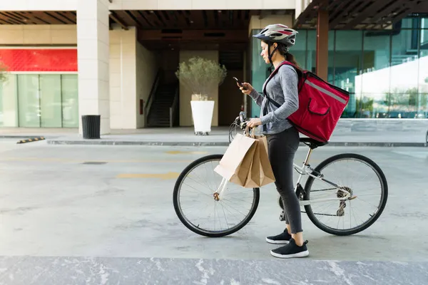 食品配送のコンセプト ラテン語の女性は 顧客にテキストを送信し 市内の自転車で配達を行う — ストック写真