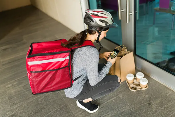 オフィスで非接触食品を配達し 注文の写真を撮る安全ヘルメットを持つ若い女性 — ストック写真