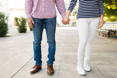 Güneşli bir günde romantik bir buluşmanın tadını çıkarırken el ele tutuşan genç bir çiftin yakınlaşması. 