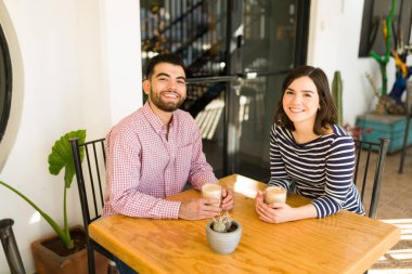 Çekici bir çiftin portresi bir kafede kahve içerken ve buluşurken gülümsüyor. 