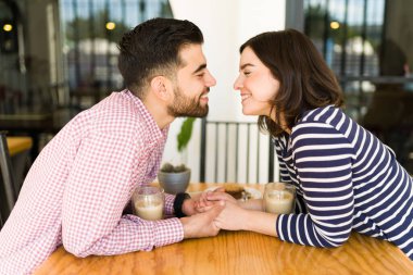 Genç aşıklar. Romantik çift, restoranda randevudayken birbirlerine bakıp öpüşmek üzereler. 