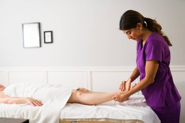 Profesyonel terapist spa 'da çalışıyor ve beyaz, olgun bir kadına ayak masajı yapıyor. 