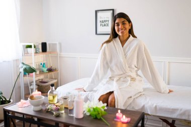 20 'li yaşlarda güzel, mutlu bir kadın. Bornoz giyiyor. Gülümsüyor ve masaj için kaplıcaya gidiyor.